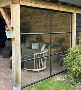 Wand van staal en glas met stopverf onder overkapping, By Siebendesign