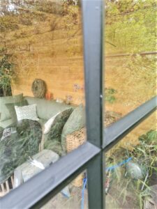 Wand van staal en glas met stopverf onder overkapping, By Siebendesign