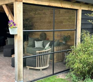Wand van staal en glas met stopverf onder overkapping, By Siebendesign